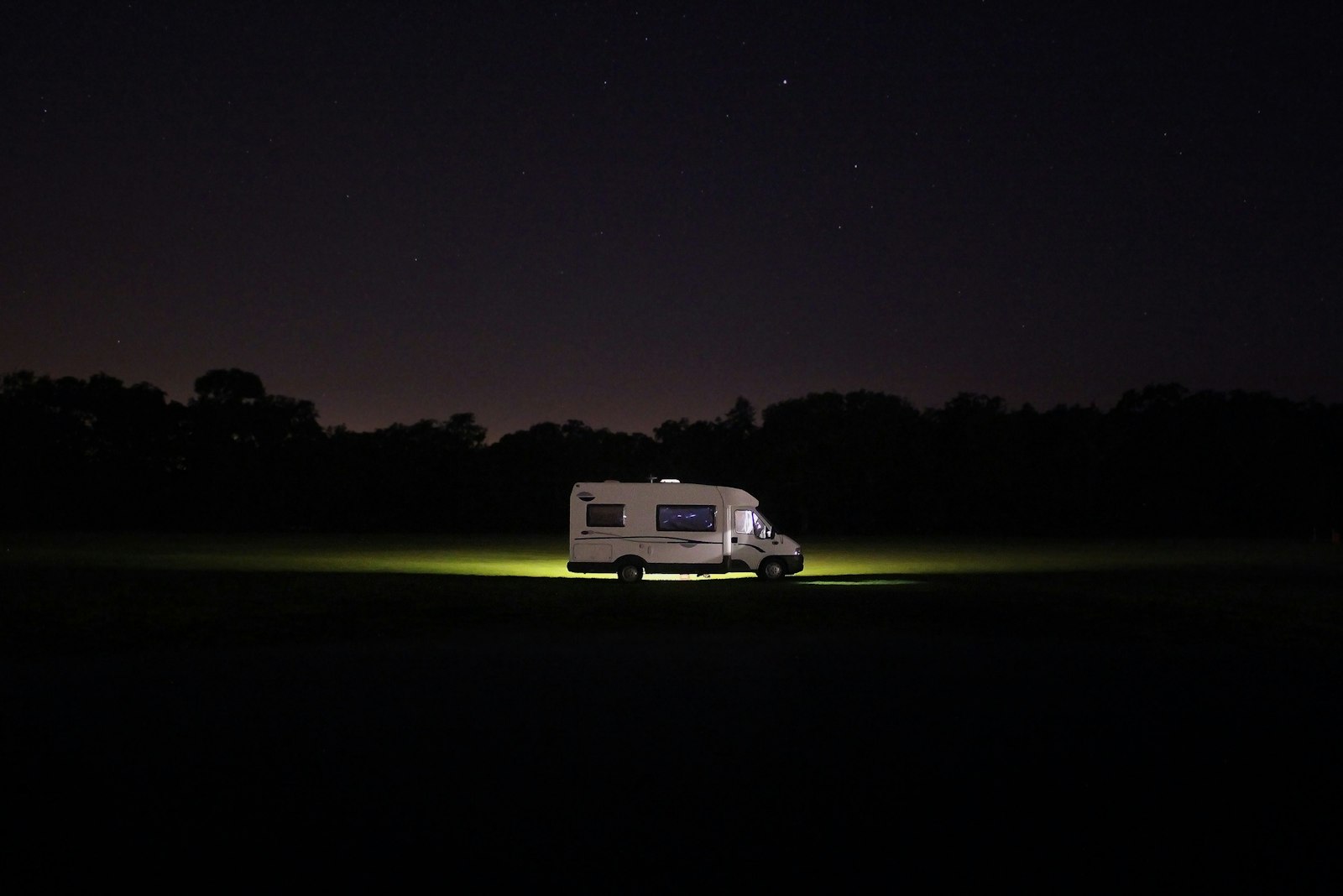 A campervan parked in a field at dusk